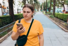 zamračená žena se dívá na displej telefonu