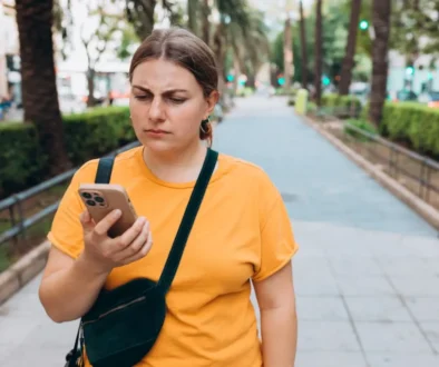 zamračená žena se dívá na displej telefonu