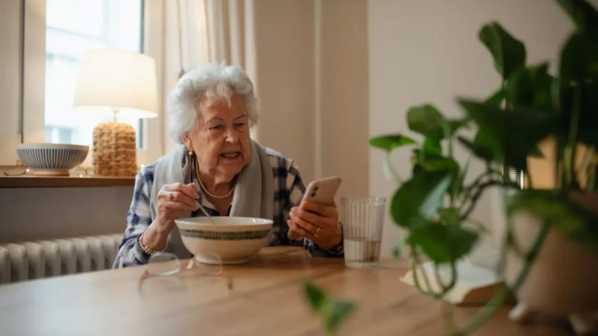 seniorka jí a dívá se na telefon