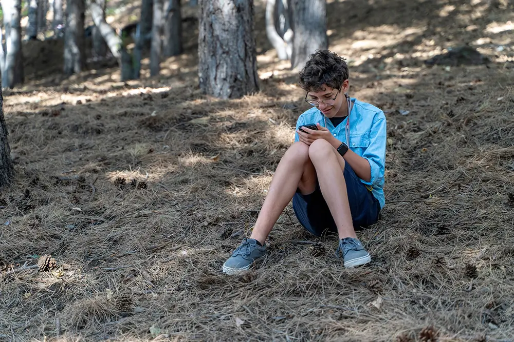 teenager v lese hraje hy na mobilu