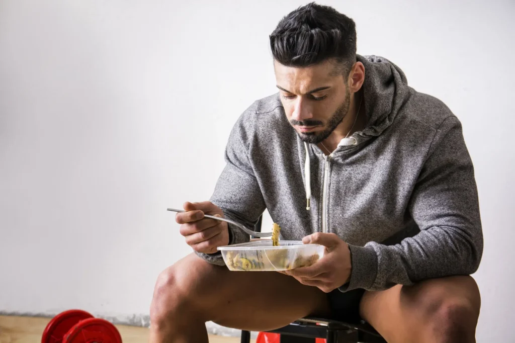 Jídlo těsně před tréninkem je pro organismus zátěží. - SportDeník muž jí jídlo z krabičky