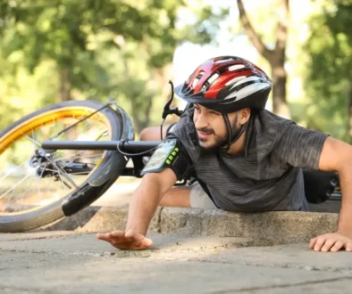 Mladý muž ve sportovním oděvu leží na zemi vedle svého kola po pádu