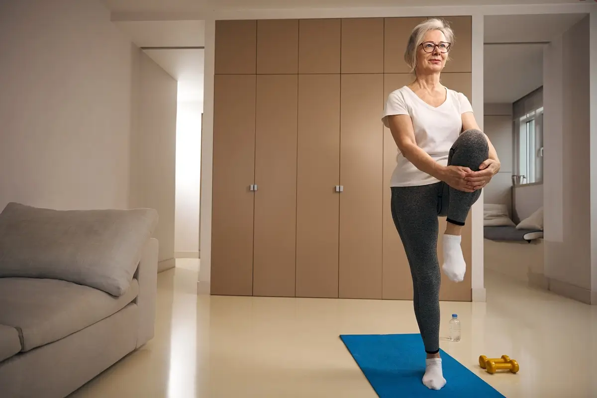 test 2 - SportDeník Žena ve zralém věku ve sportovním oděvu stojí na jedné noze na karimatce