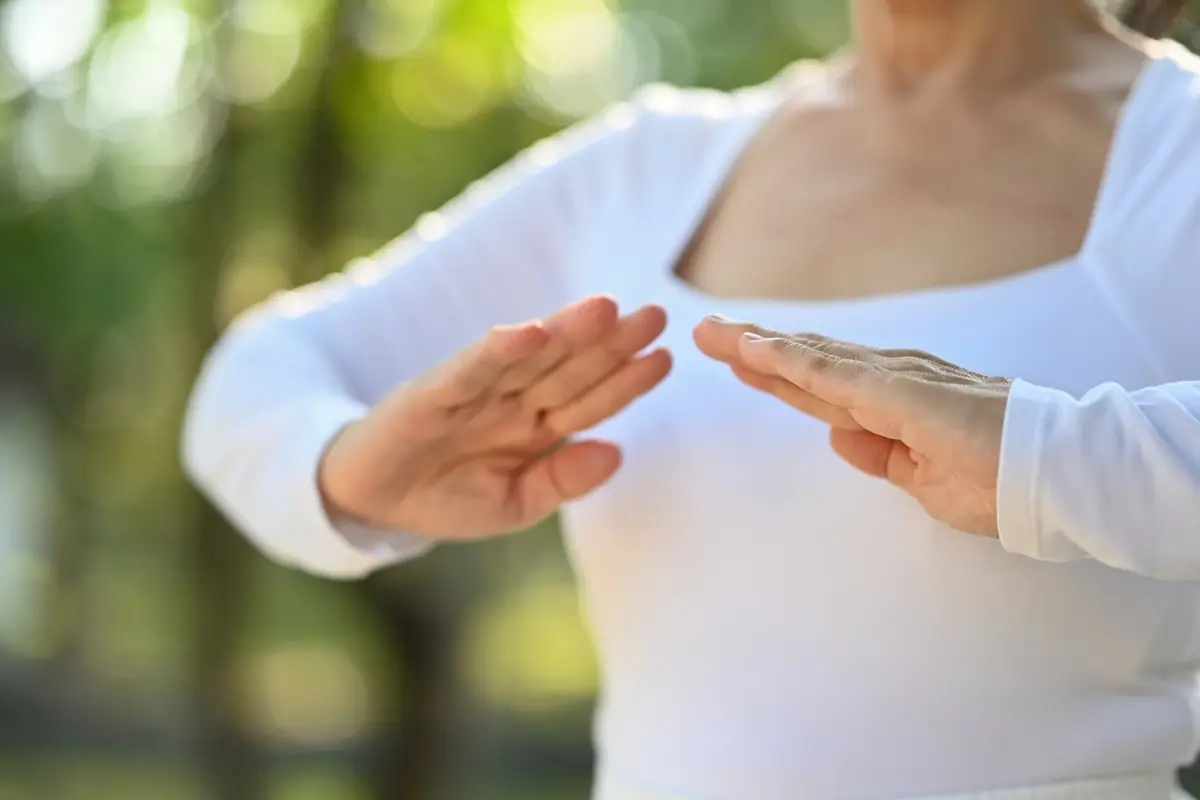 test 3 - SportDeník Horní část ženského těla v bílém tričku, cvičící tai-chi