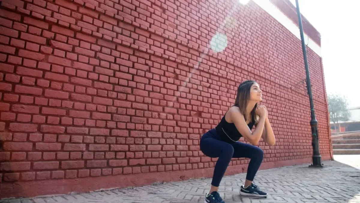 Mladá žena ve sportovním oděvu provádí hluboký dřep
