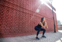 Mladá žena ve sportovním oděvu provádí hluboký dřep