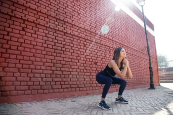 Mladá žena ve sportovním oděvu provádí hluboký dřep