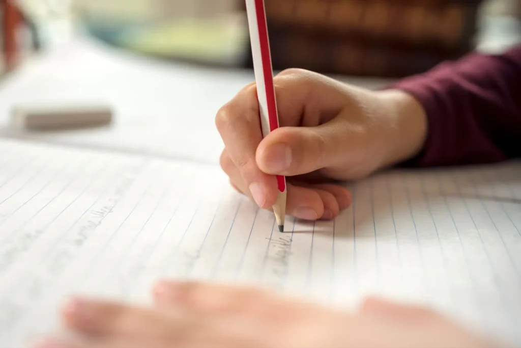 ruka studenta zapisující poznámky do sešitu