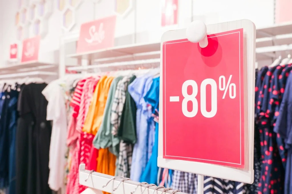 Shutterstock_1466590637 - SportDeník Cedule u regálu s oděvy s nápisem -80 %
