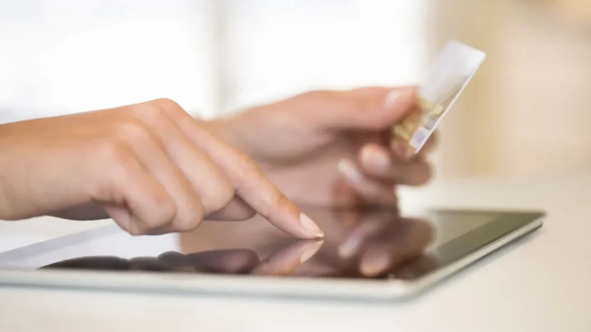 ženské ruce držící platební kartu a ťukající do tabletu