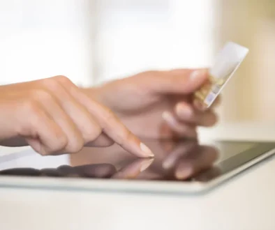 ženské ruce držící platební kartu a ťukající do tabletu