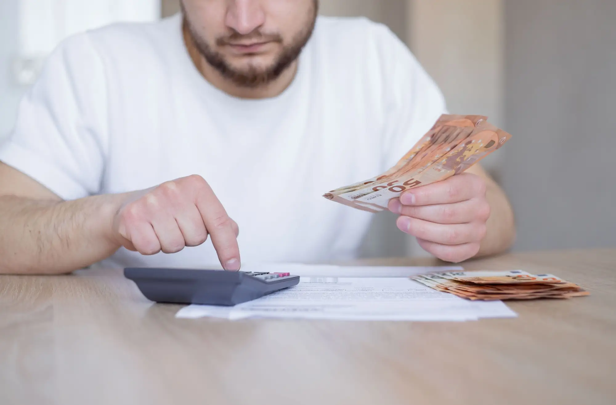 Muž s kalkulačkou a euro bankovkami