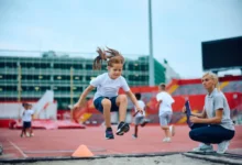 Žačka skáče do dálky před učitelkou