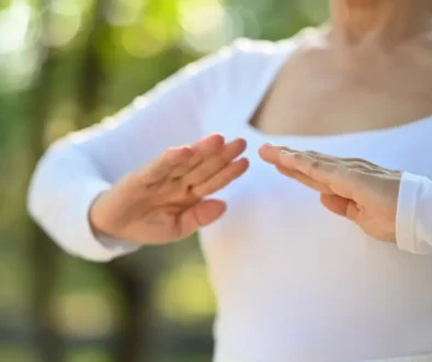 Starší žena v bílém tričku cvičí tai-chi