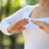 Starší žena v bílém tričku cvičí tai-chi