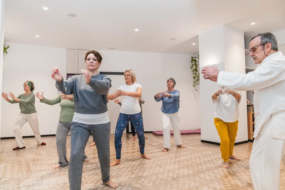 Tai-chi 3 - SportDeník Skupina lidí pokročilejšího věku cvičí tai-chi v tělocvičně