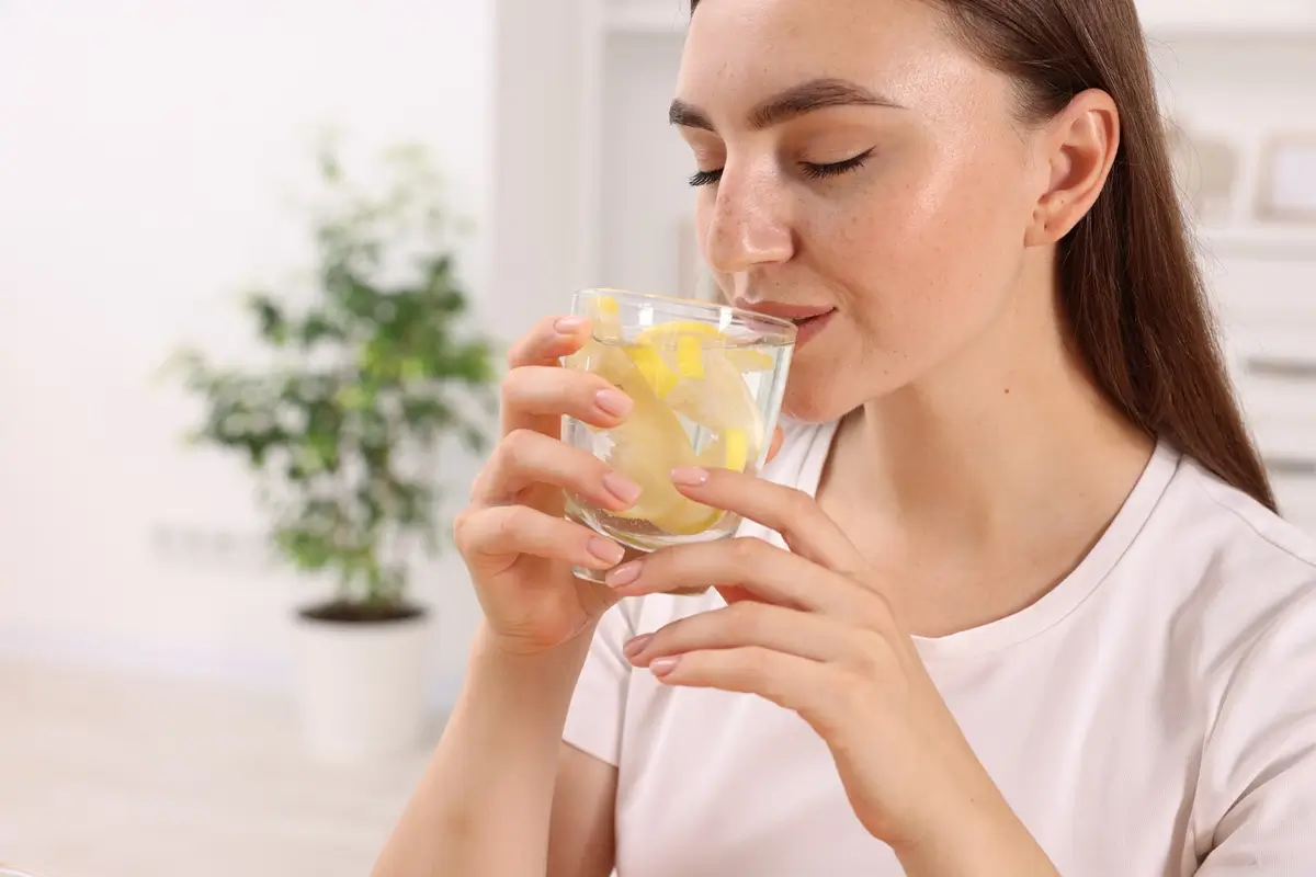 Mladá žena popíjí vodu s citronem 