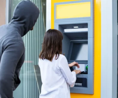 žena u bankomatu a za ní zloděj