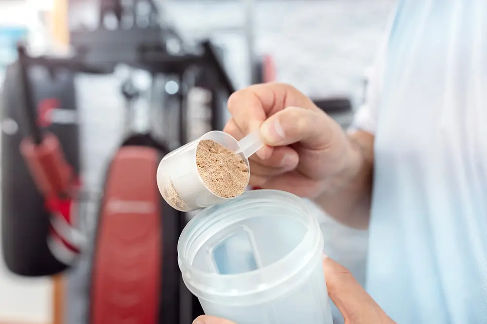 muž si sype protein do šejkru