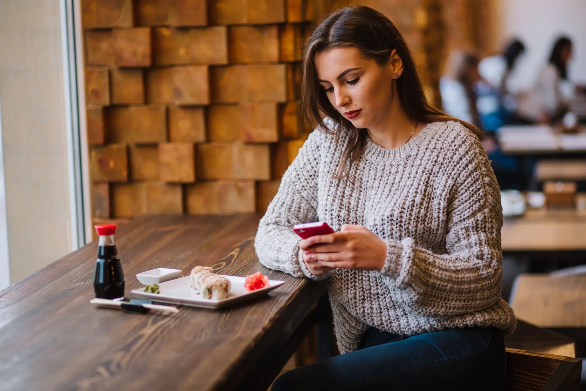 Žena s mobilem v restauraci