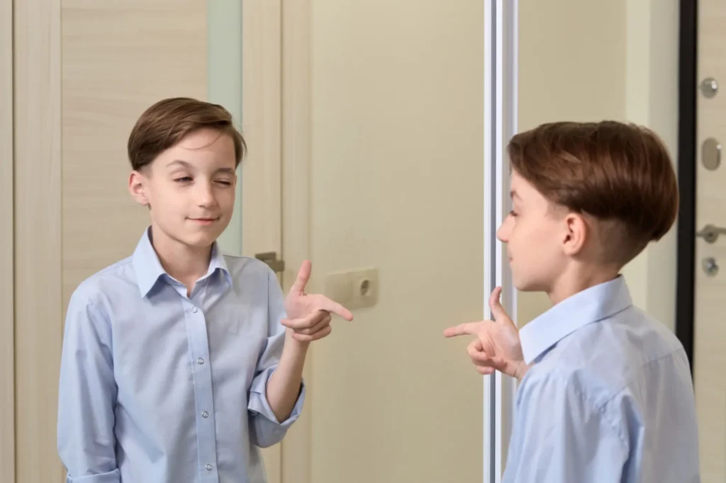 Kluk mrkající jedním okem před zrcadlem