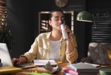 Žena při práci pije energetický nápoj