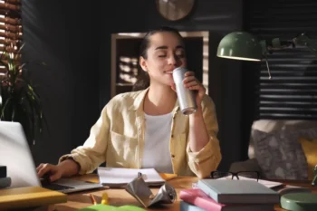 Žena při práci pije energetický nápoj