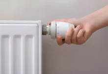 Ruka otáčí ventilem na radiátoru