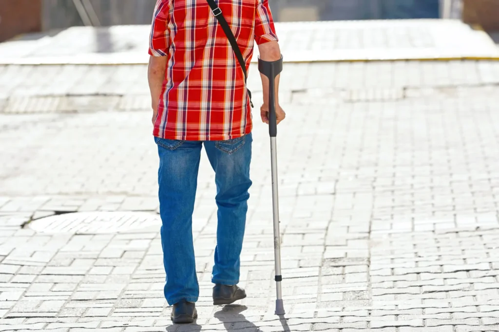 Senior s holí přecházející silnici