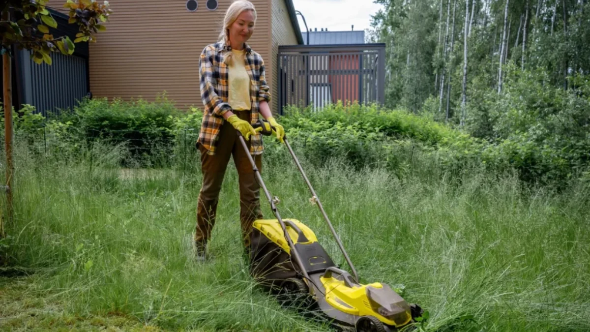 Žena seká trávu na zahradě
