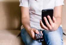 žena s ovladačem od televize a mobilem