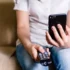 žena s ovladačem od televize a mobilem