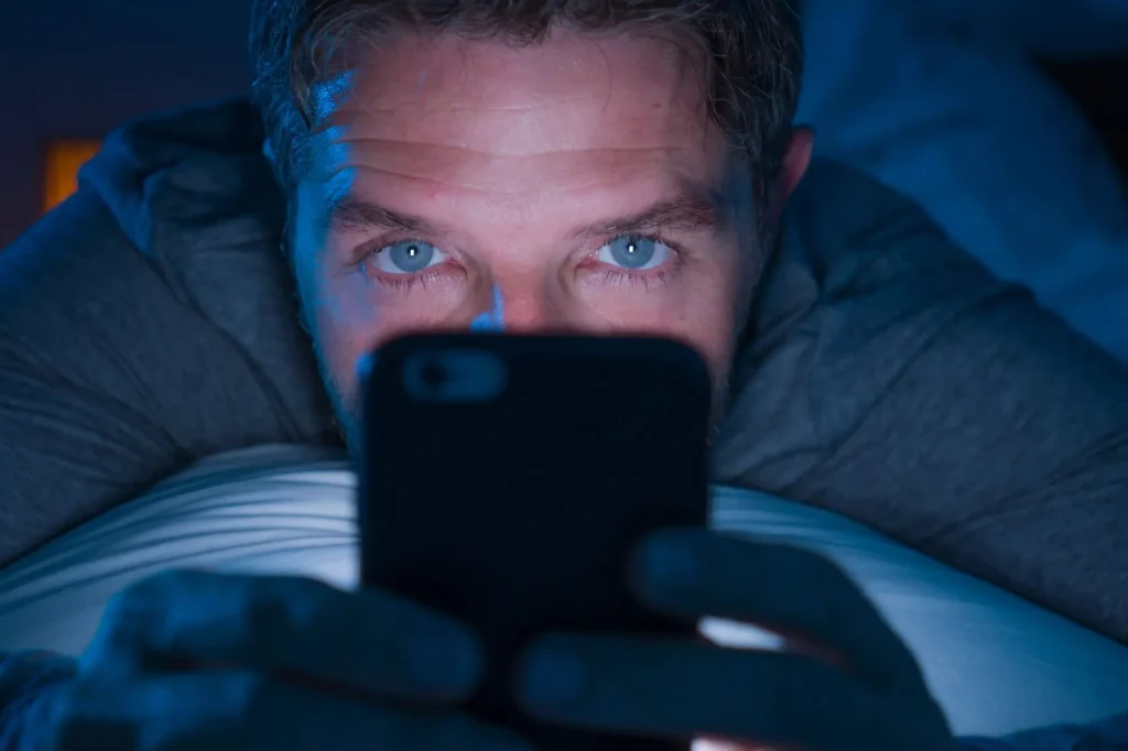 muž se dívá v noci na displej telefonu
