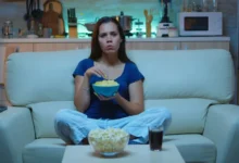 žena jí chipsy na gauči