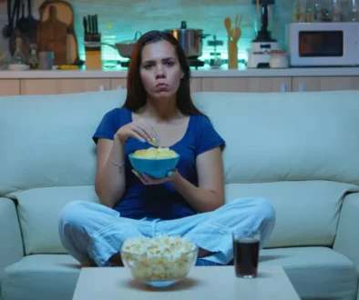 žena jí chipsy na gauči