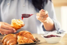 žena si na croissant dává marmeládu