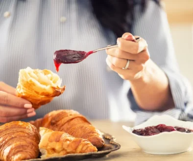 žena si na croissant dává marmeládu