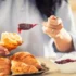 žena si na croissant dává marmeládu