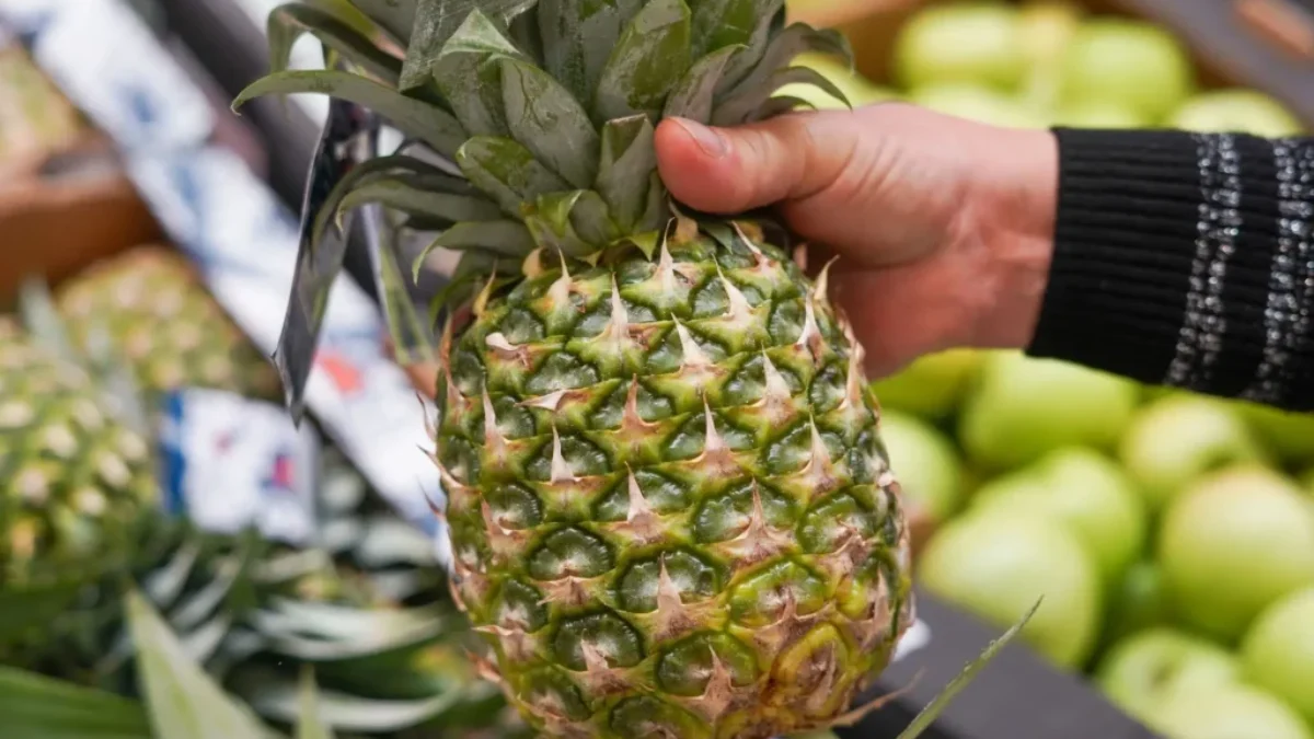 detail na ruku v supermarketu držící ananas