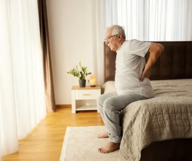senior vstává z postele a drží se záda
