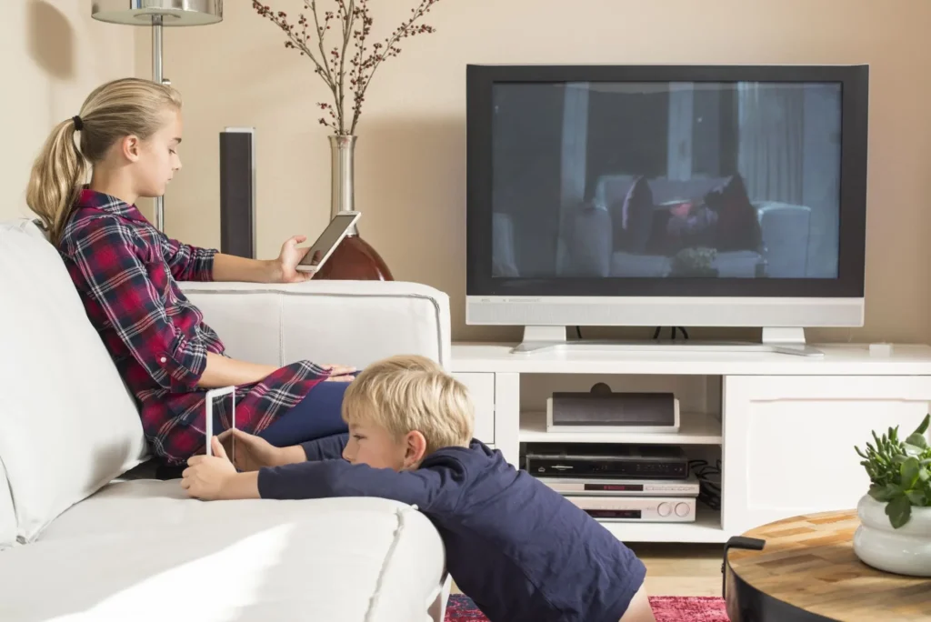 děti sedí v obýváku u telefonů a televize