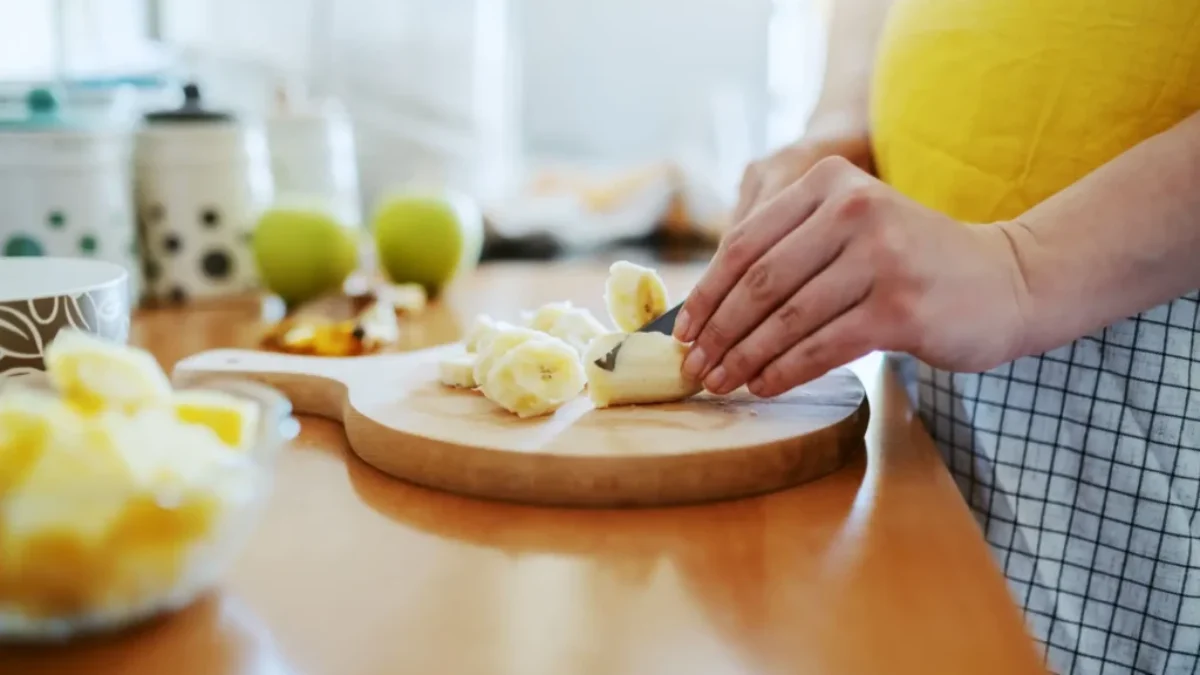 žena krájí na prkénku banán