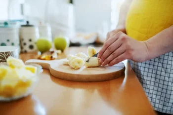 žena krájí na prkénku banán