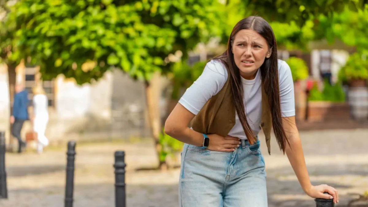 mladá dívka se drží za břicho