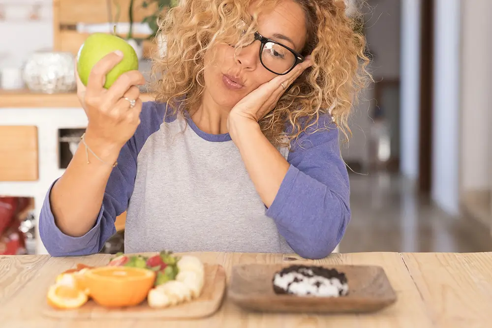 žena rozmýšlí mezi donutem a ovocem