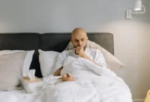 muž leží v posteli s kašlem