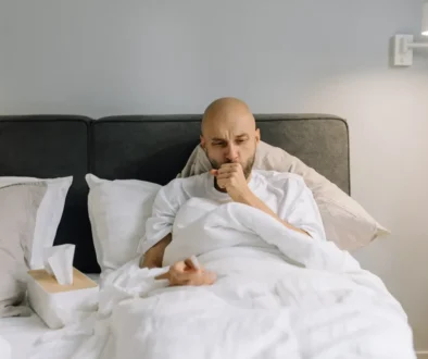muž leží v posteli s kašlem