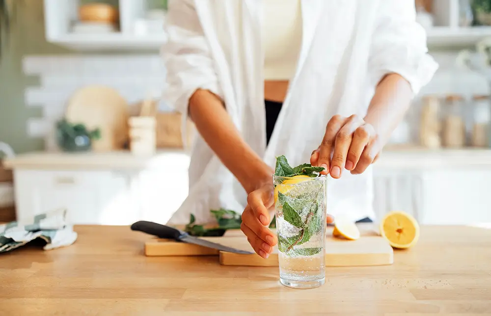 Vodu si můžete ochutit bylinkami a citrusy. - SportDeník žena dává bylinky do vody